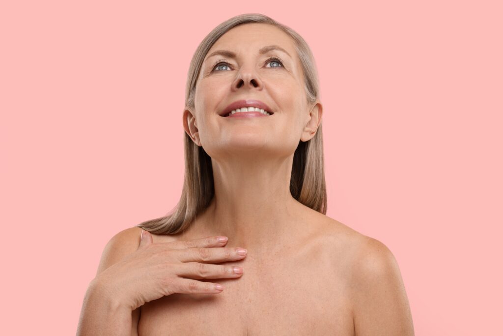 A woman smiling with her hand on her chest, showing the results of Genius RF microneedling