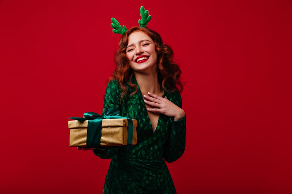 Woman dressed in holiday attire, smiling with perfect smooth skin from facial rejuvenation.